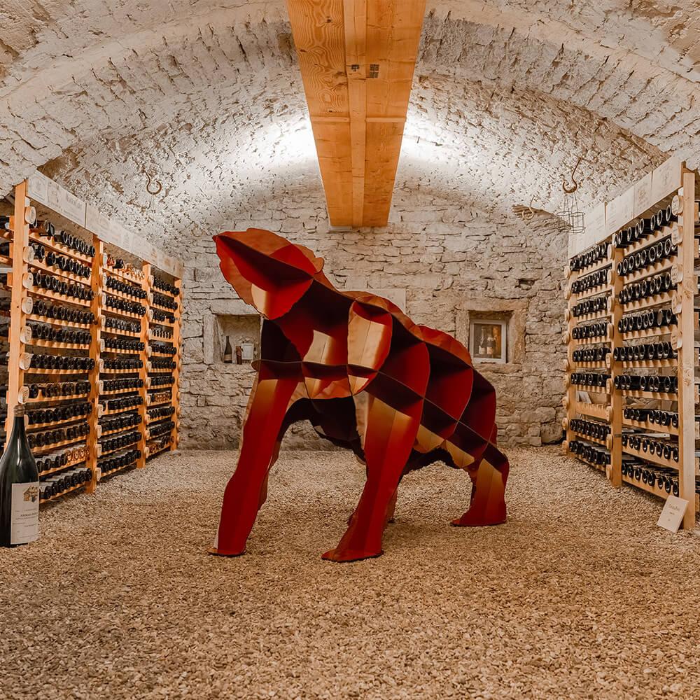 Mobilier animal en forme d'ours géant rouge dans une cave à vin. Marque Ibride design
