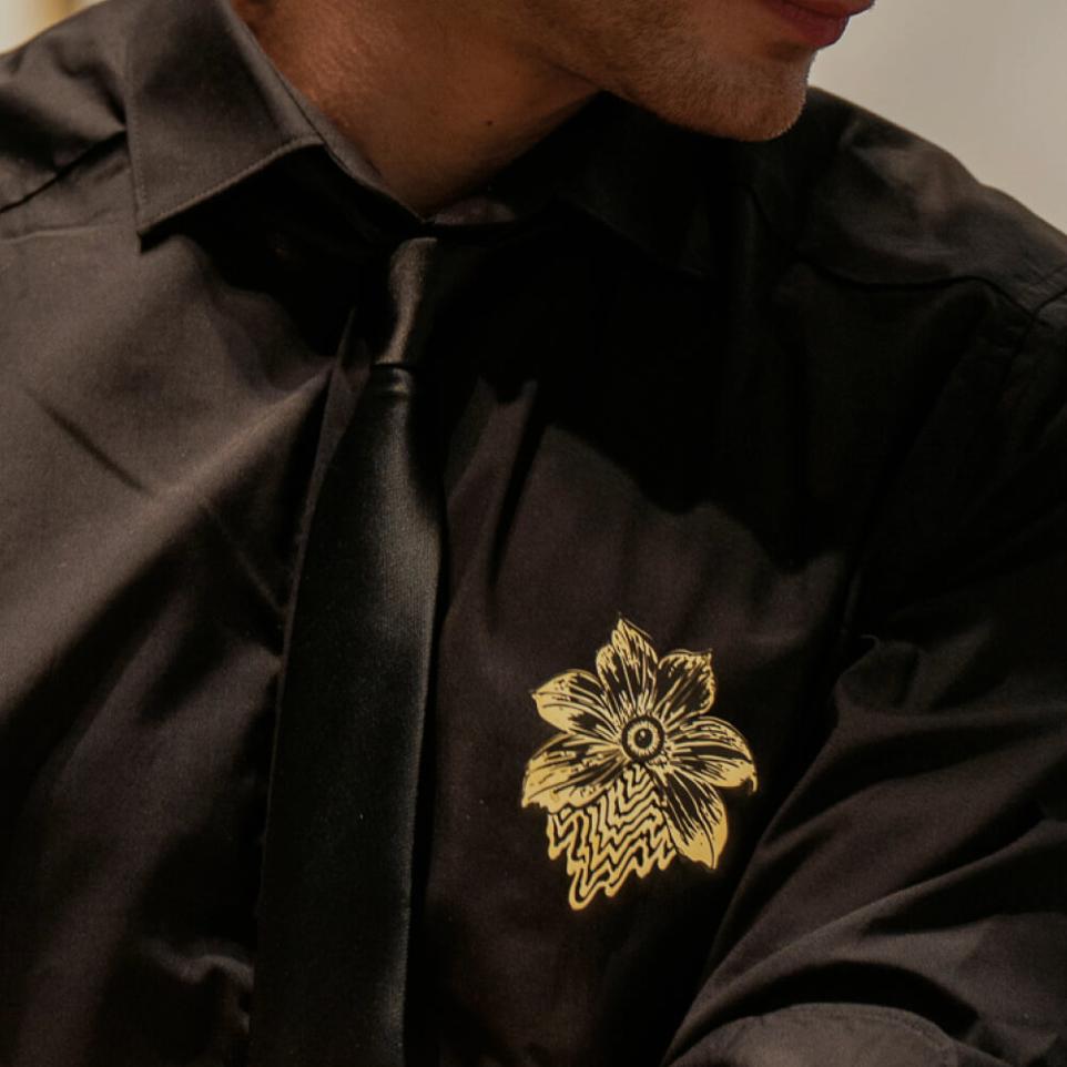 Bijou Hope Obsidian Noir Broche en laiton doré et noir portée sur un vêtement, une chemise noire. Broche de la marque Ibride